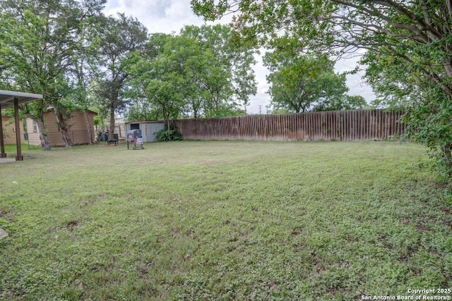 view of yard with an outdoor structure, fence, and a storage unit