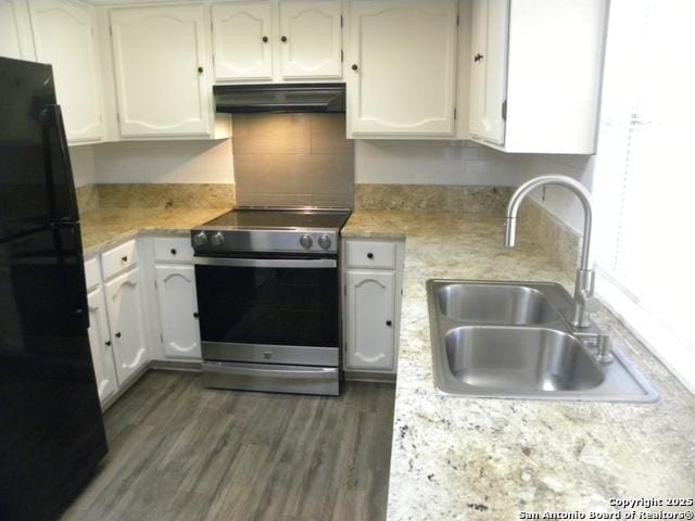 kitchen with freestanding refrigerator, white cabinetry, under cabinet range hood, stainless steel electric stove, and a sink