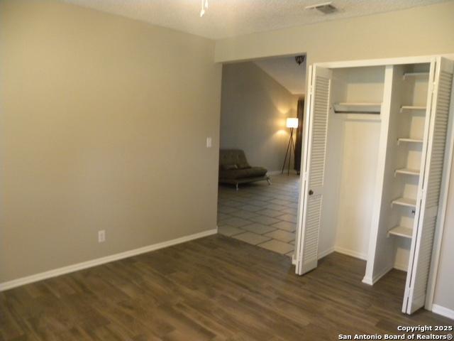unfurnished bedroom featuring baseboards, a closet, dark wood-style flooring, and visible vents