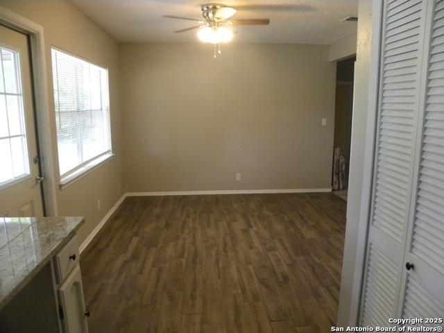 unfurnished dining area with baseboards, a ceiling fan, and dark wood finished floors