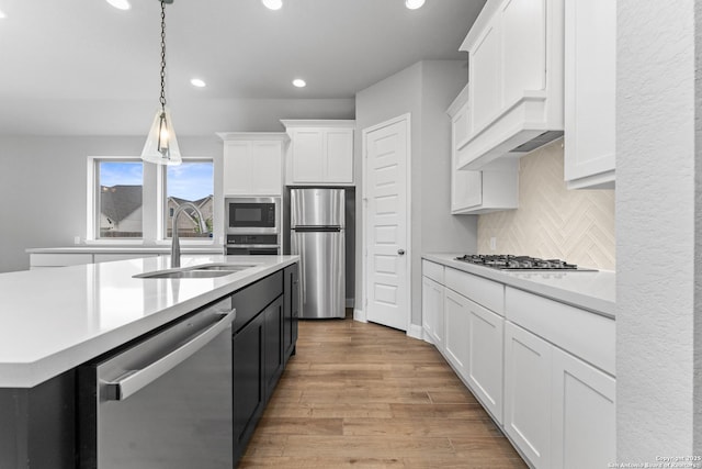 kitchen with recessed lighting, light countertops, a sink, appliances with stainless steel finishes, and white cabinetry