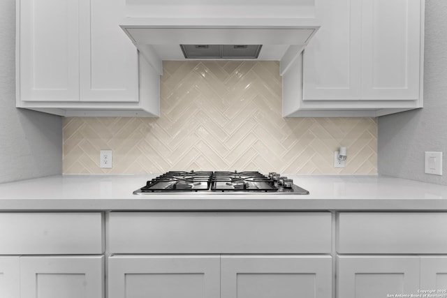 kitchen with custom exhaust hood, white cabinets, stainless steel gas cooktop, light countertops, and backsplash