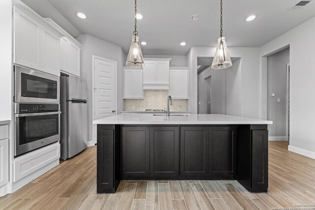 kitchen with light countertops, light wood-style flooring, appliances with stainless steel finishes, and a sink