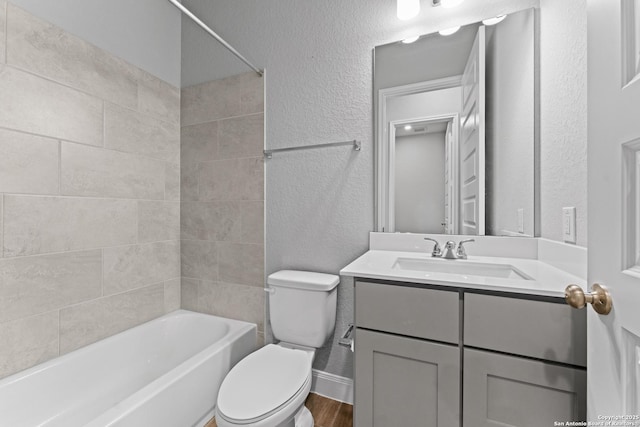 full bathroom featuring toilet, wood finished floors, a textured wall, vanity, and shower / tub combination