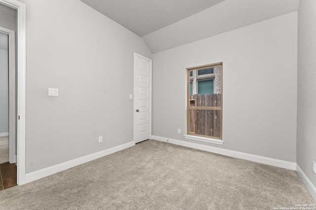 spare room featuring vaulted ceiling, baseboards, and carpet