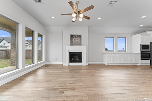 unfurnished living room featuring recessed lighting, a wealth of natural light, visible vents, and light wood-type flooring