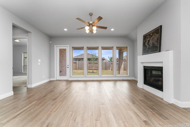 unfurnished living room featuring baseboards, a ceiling fan, a glass covered fireplace, and light wood-style flooring