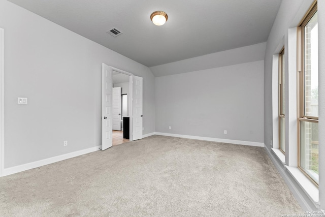 unfurnished bedroom with baseboards, lofted ceiling, carpet flooring, and visible vents