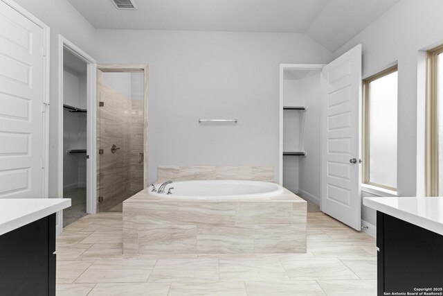 full bath with a garden tub, a stall shower, a walk in closet, vanity, and visible vents