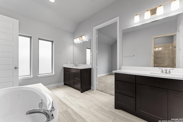 full bath with a garden tub, lofted ceiling, two vanities, and a sink