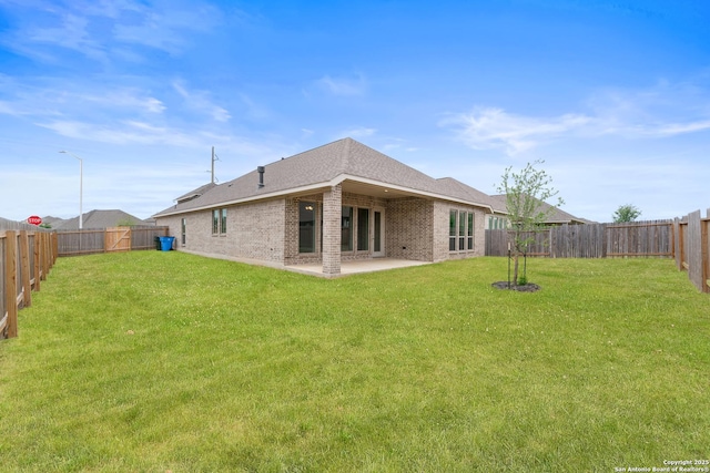 back of house featuring a fenced backyard, brick siding, and a yard