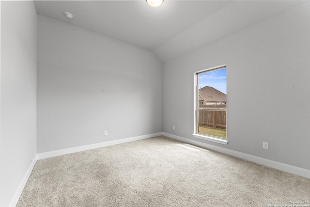 carpeted spare room with lofted ceiling and baseboards