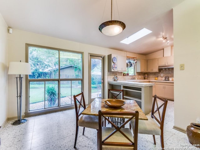 dining area featuring baseboards and vaulted ceiling with skylight