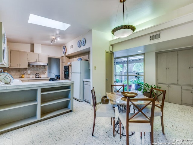 dining area featuring light floors, a skylight, visible vents, and rail lighting