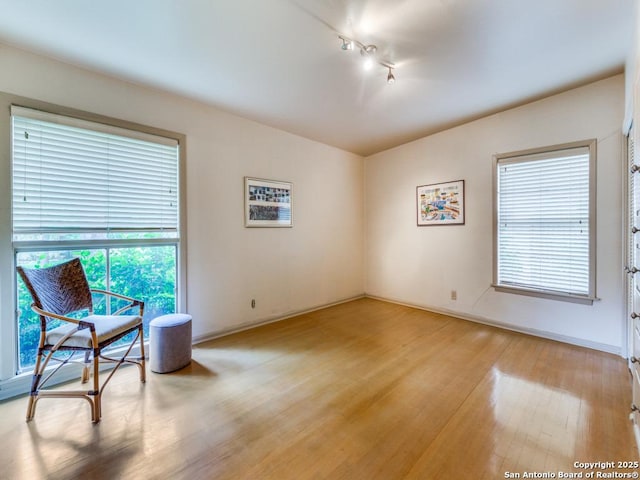 unfurnished room featuring light wood finished floors, baseboards, and rail lighting