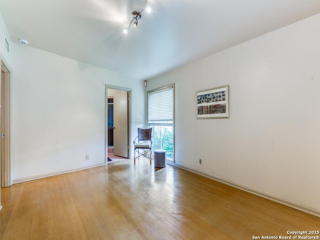 interior space featuring light wood finished floors, track lighting, and baseboards