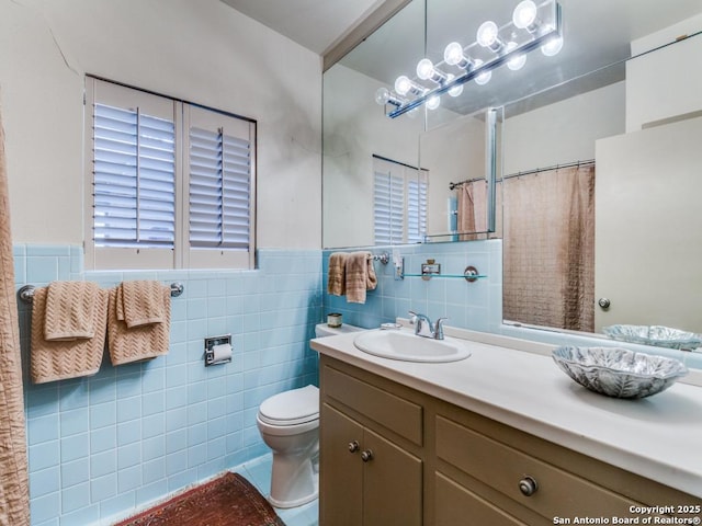 bathroom with wainscoting, toilet, vanity, and tile walls