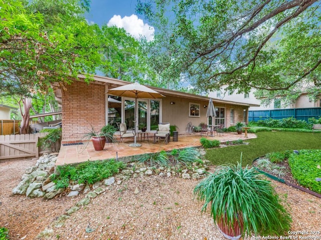 rear view of property featuring brick siding, a patio area, and a fenced backyard