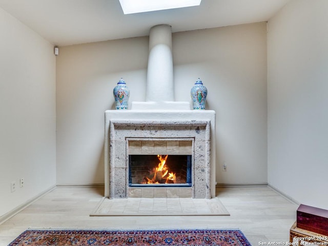 details with a tile fireplace, baseboards, wood finished floors, and a skylight