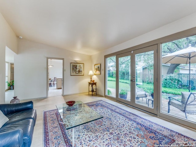 living area with light wood-type flooring, a wealth of natural light, baseboards, and french doors