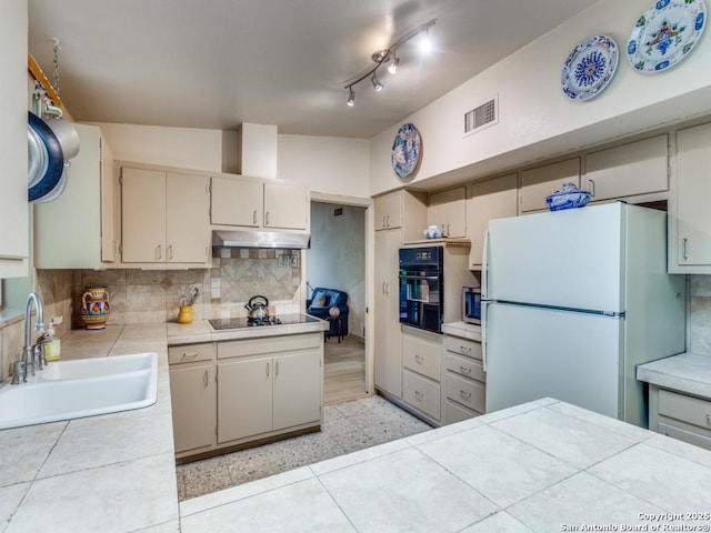kitchen with a sink, visible vents, decorative backsplash, under cabinet range hood, and black appliances
