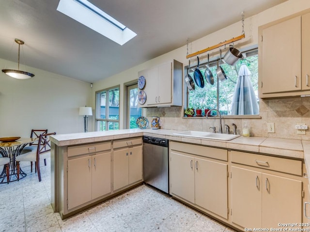 kitchen featuring light floors, stainless steel dishwasher, a sink, a peninsula, and tasteful backsplash