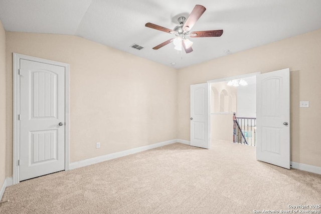 unfurnished room featuring carpet, vaulted ceiling, visible vents, a ceiling fan, and baseboards