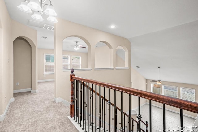 hall with visible vents, baseboards, a chandelier, carpet, and an upstairs landing