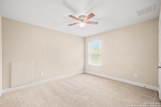 carpeted empty room with visible vents, baseboards, and ceiling fan