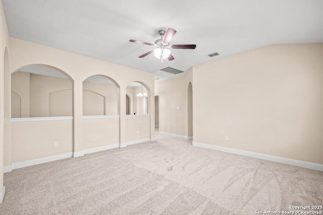 unfurnished bedroom with arched walkways, visible vents, and carpet