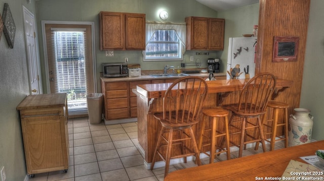 kitchen featuring stainless steel microwave, plenty of natural light, brown cabinets, and a sink