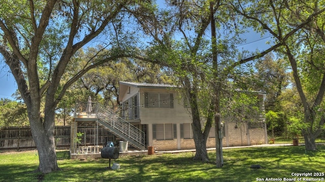 exterior space featuring a wooden deck, fence, a yard, and stairs