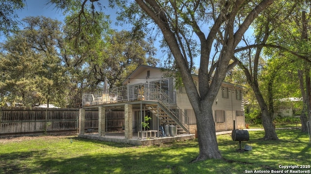 rear view of property with a wooden deck, stairway, fence, and a yard