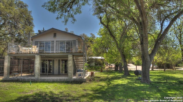 rear view of property with stairway, a balcony, a lawn, fence, and a patio