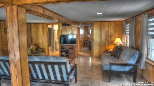 living room featuring wooden walls, visible vents, and finished concrete floors