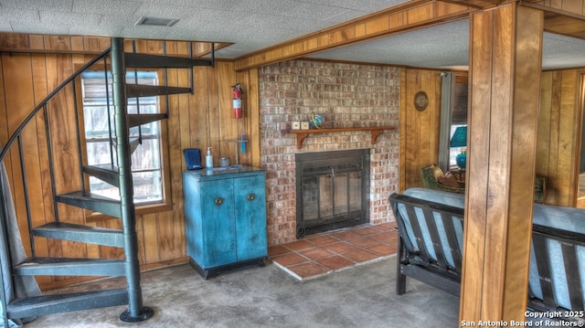 living area featuring carpet, wooden walls, a fireplace, and stairs