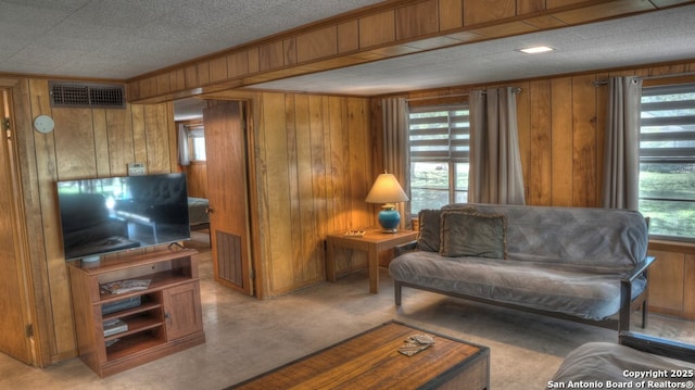 living area with visible vents, wood walls, and ornamental molding
