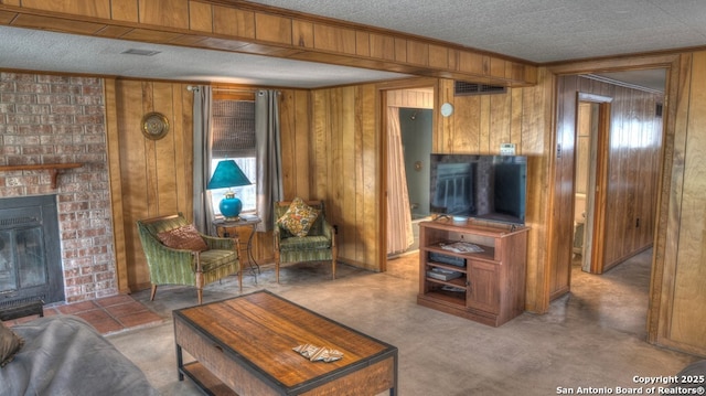 living area featuring wooden walls, visible vents, ornamental molding, a fireplace, and a textured ceiling