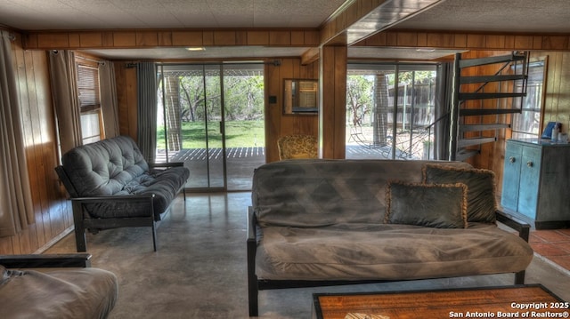 living room featuring wood walls, concrete floors, and a textured ceiling