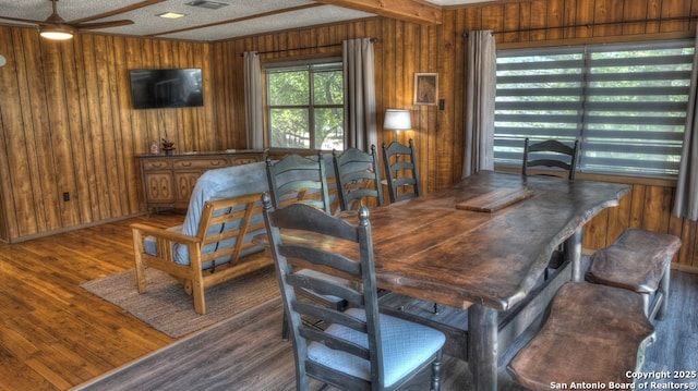 dining room featuring wood finished floors, visible vents, wood walls, and ceiling fan