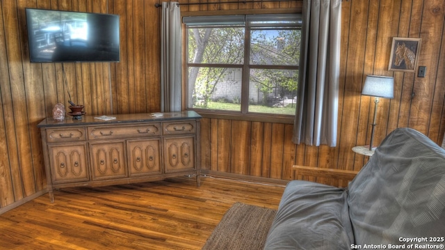 living area with dark wood-type flooring and wooden walls