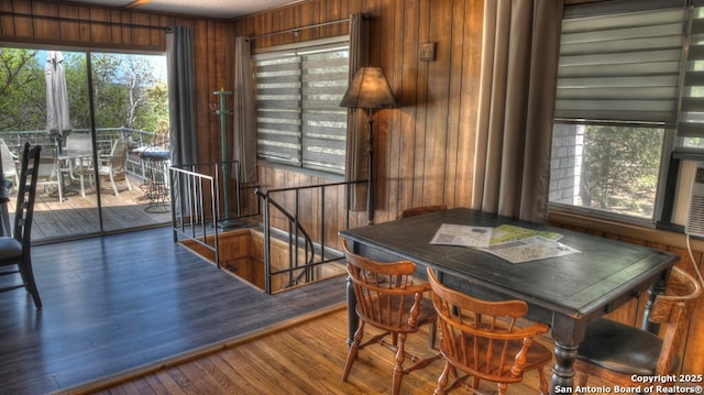 dining area with wood finished floors, wooden walls, and plenty of natural light