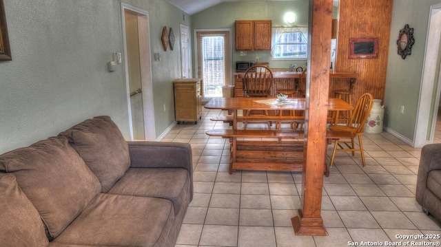 dining area with vaulted ceiling, baseboards, and light tile patterned flooring