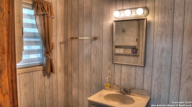 bathroom featuring a sink and wooden walls