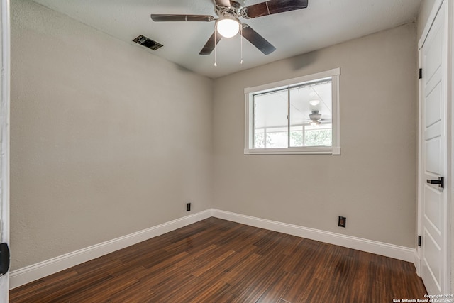 empty room with dark wood finished floors, visible vents, baseboards, and ceiling fan