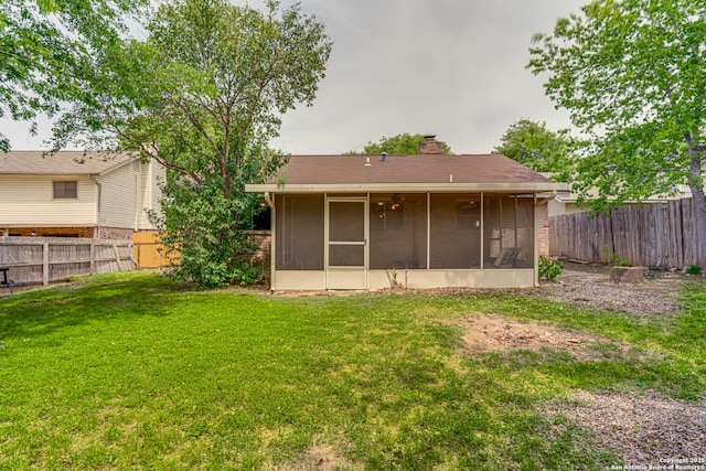 back of house with a fenced backyard, a chimney, a sunroom, and a yard