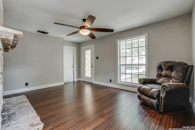 living area with baseboards, visible vents, and dark wood finished floors