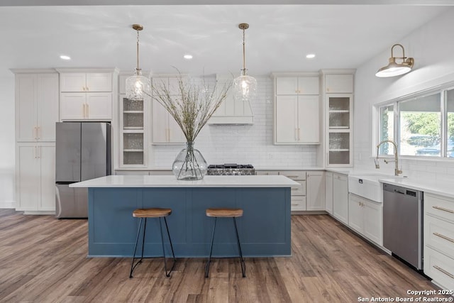 kitchen with a kitchen island, white cabinetry, stainless steel appliances, and a sink