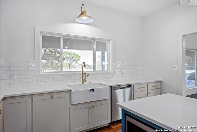 kitchen with decorative backsplash, stainless steel dishwasher, light countertops, and a sink