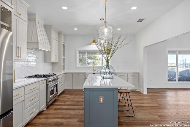 kitchen featuring stainless steel appliances, dark wood-style floors, decorative backsplash, custom range hood, and a breakfast bar